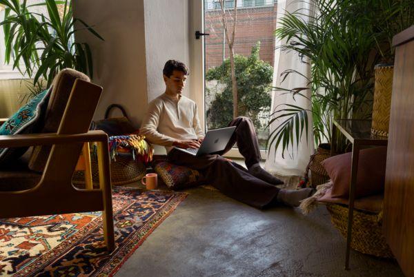 a man sitting on a chair with a MacBook Pro on the floor